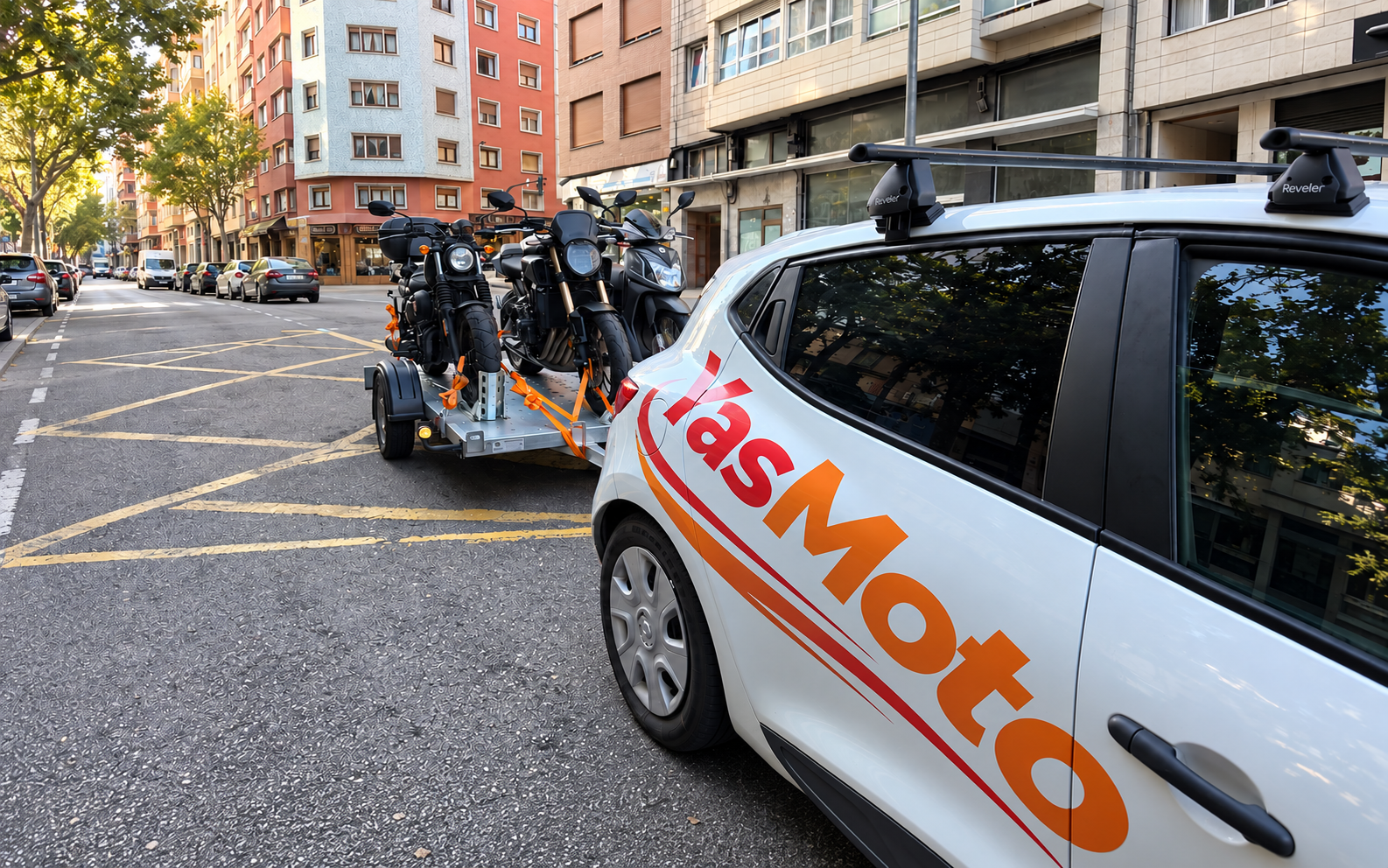 Vehículo YasMoto y tres motos sobre el remolque, en una calle de Barcelona